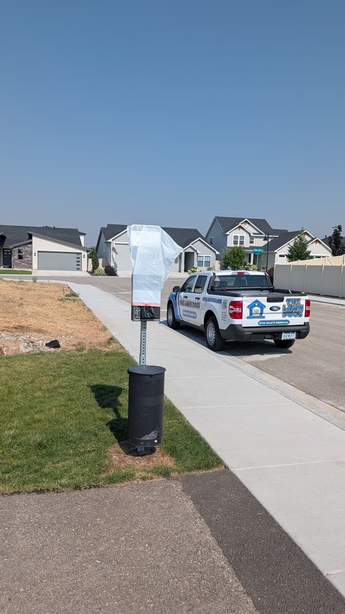 A pet waste station on a sidewalk in a new Star neighborhood off Beacon Light, with a Lawn Dogs truck parked behind it