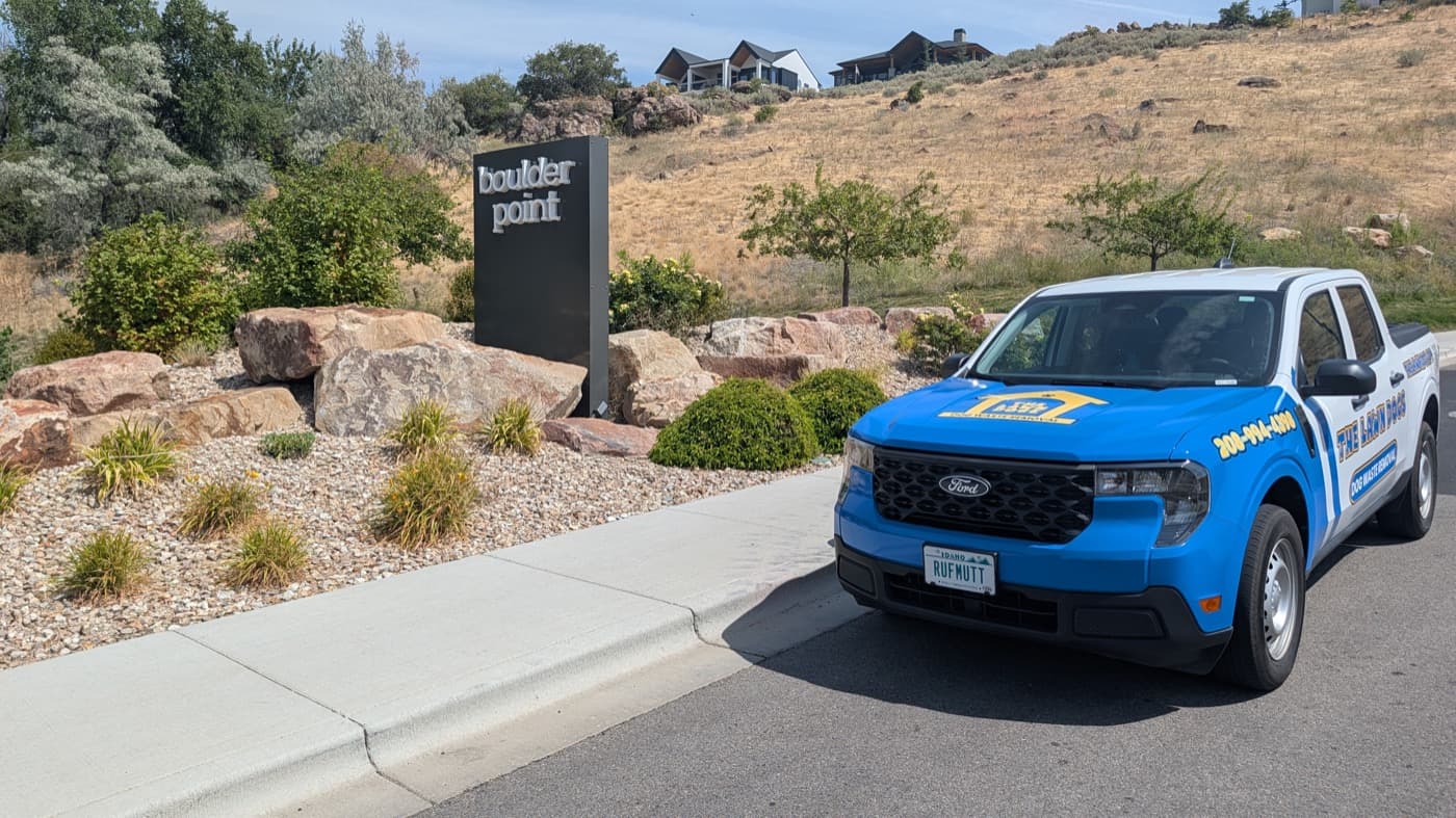 A Lawn Dogs truck parked at the Boulder Point entrance monument in the Boise foothills