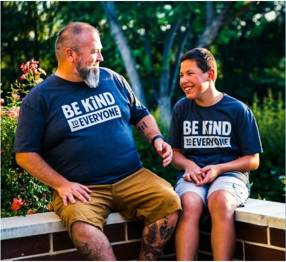 The Lawn Dogs Team - Donovan and Manny Johns smiling, wearing a "be kind" shirt